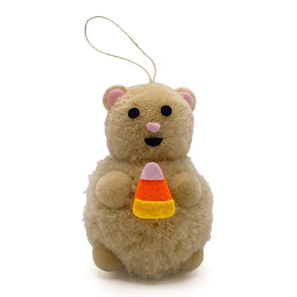 A small beige plush hamster ornament holding a candy corn, with a thin gold hanging loop at the top, shown on a plain white background.