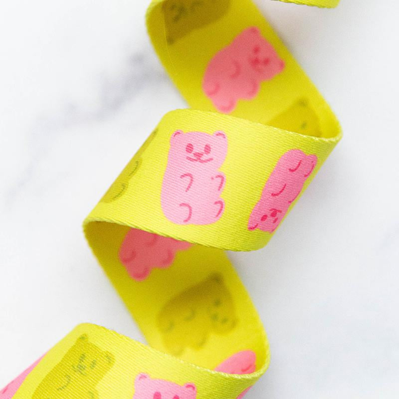 Yellow webbing with pink gummy bear designs on a white background