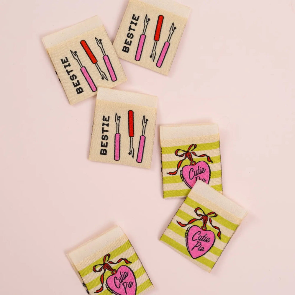 Set of small rectangular labels with illustrations and text on a pink background