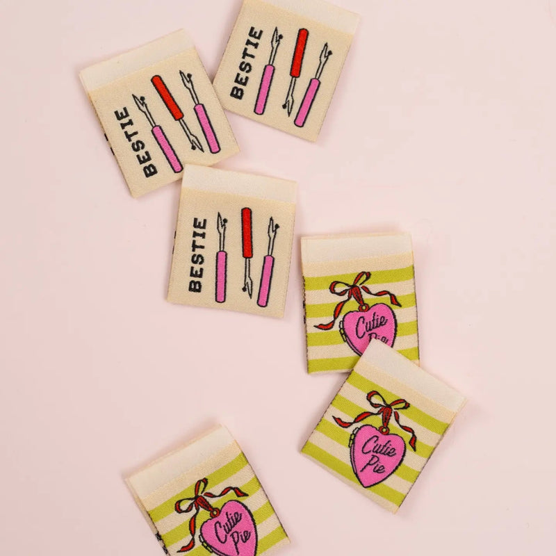 Set of small rectangular labels with illustrations and text on a pink background