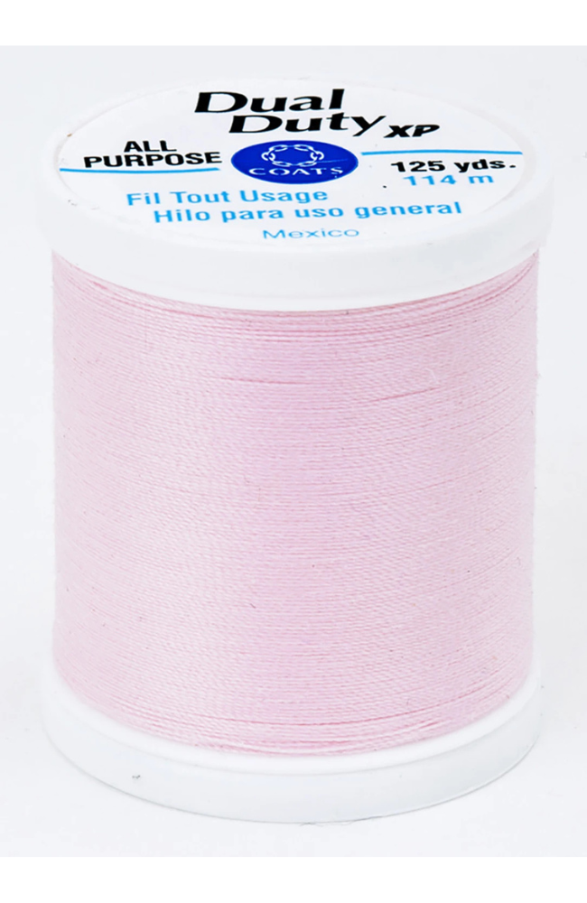 A spool of light pink Dual Duty XP sewing thread on a white plastic spool with a white lid, photographed against a plain white background.