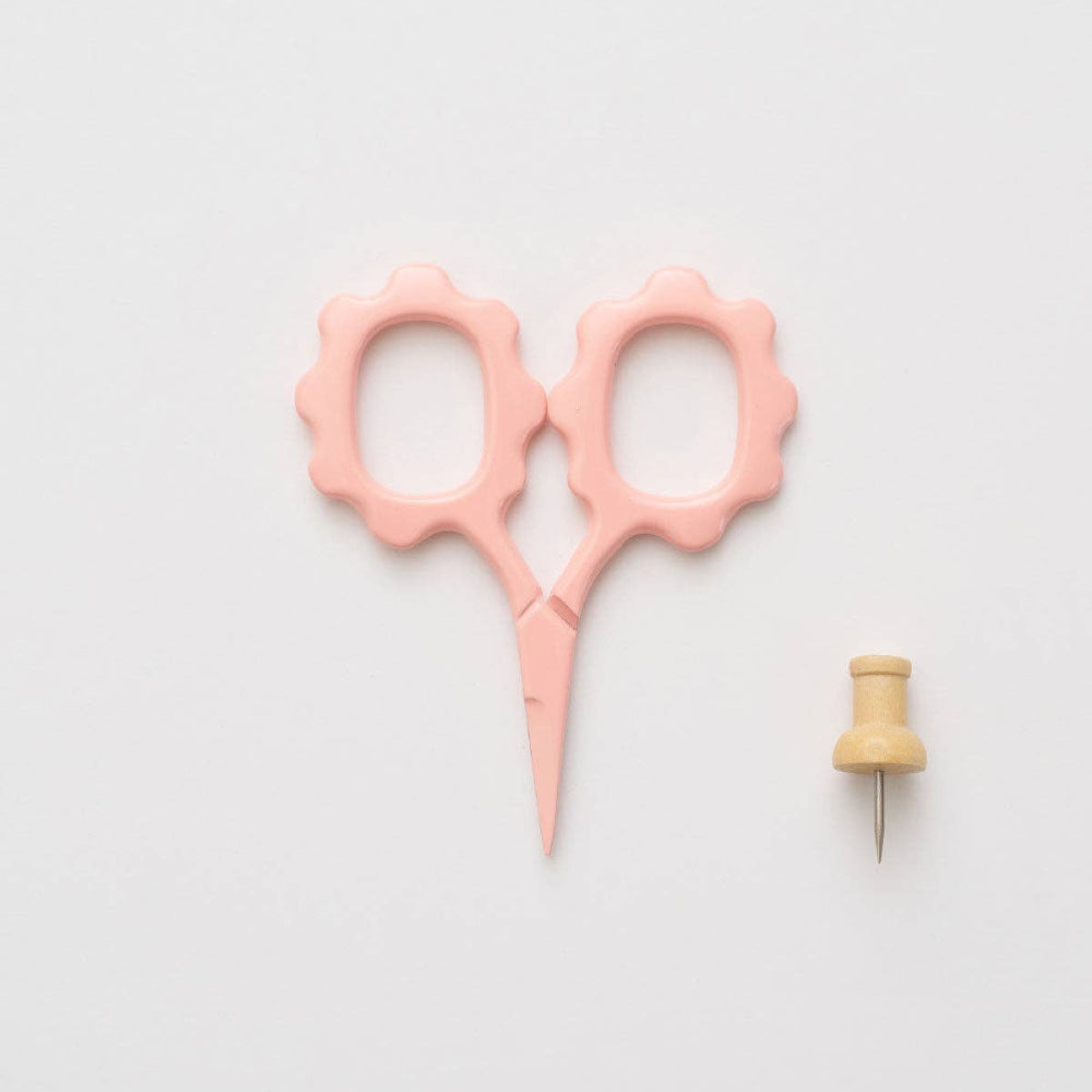 Pink scissors and wooden pin on a light gray background