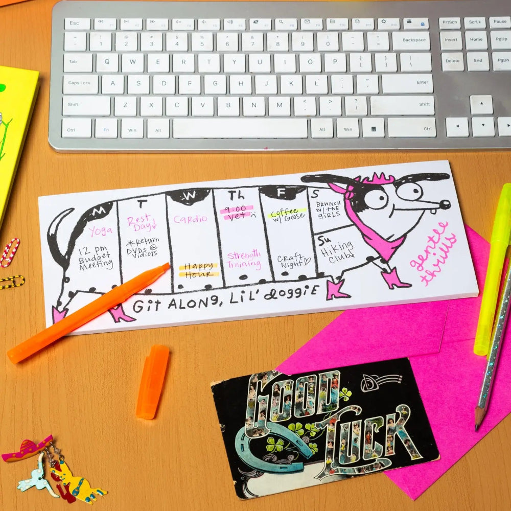 Desk with a keyboard, colorful planner, and stationery items on a wooden surface