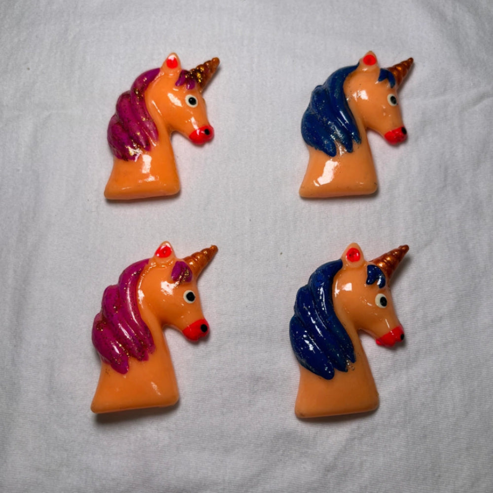 4 unicorn head magnets on a white background. Two have pink hair and two have blue hair.