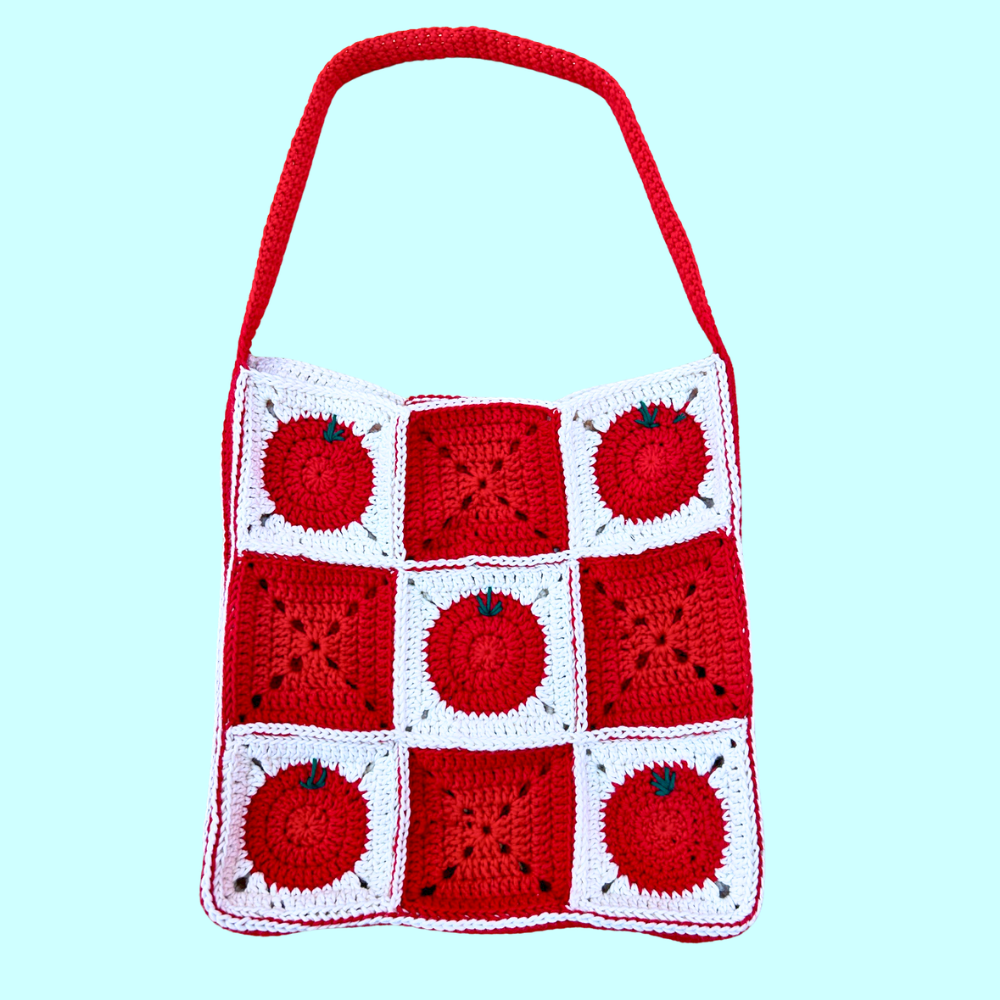 Red and white crochet granny square tote bag featuring some squares with a tomato design on a light blue background.