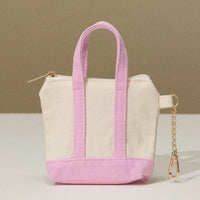 Mini tote bag with pink bottom and handles, zip top, and key chain on the side.