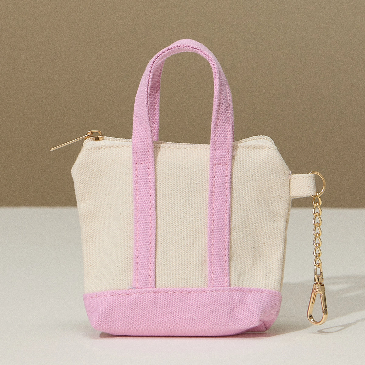 Mini tote bag with pink bottom and handles, zip top, and key chain on the side.