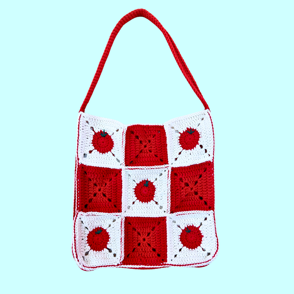 Red and white crochet granny square tote bag featuring some squares with a tomato design on a light blue background.