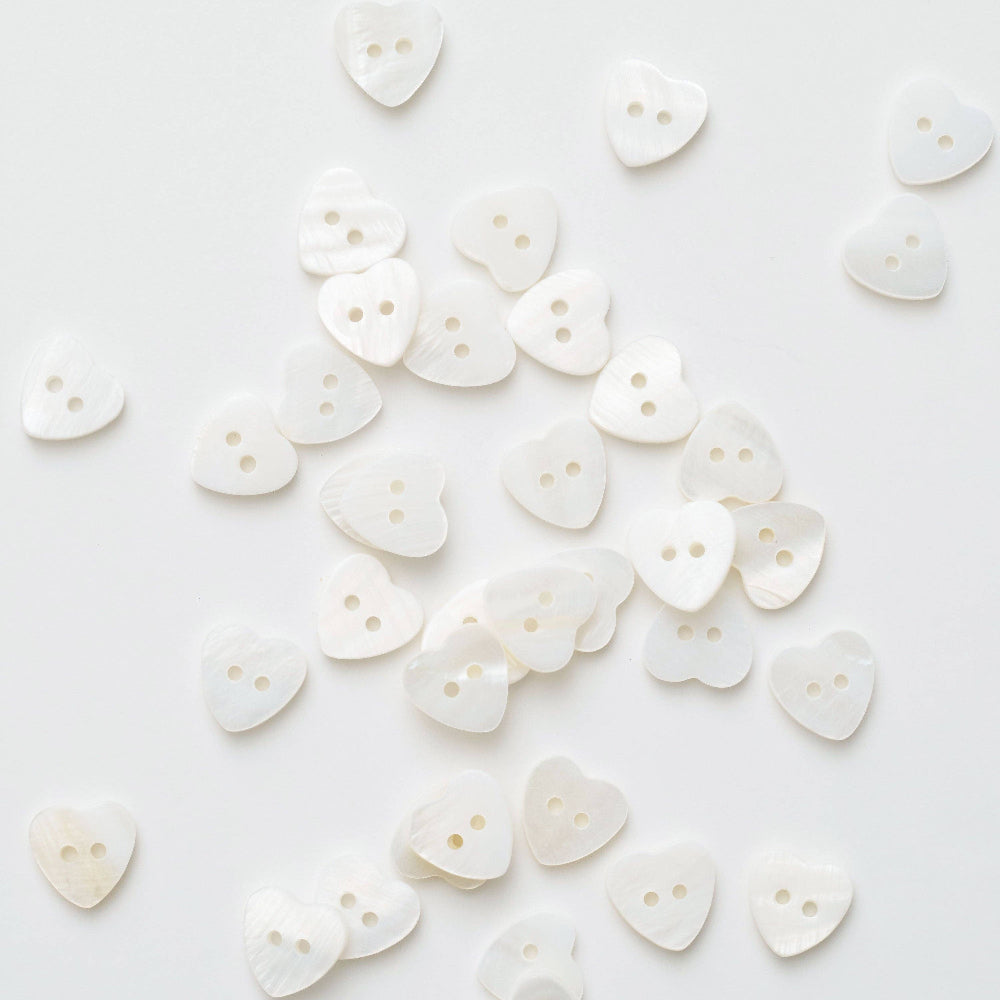 White heart-shaped buttons scattered on a white background