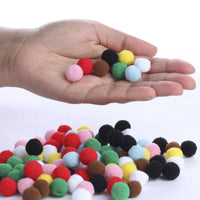 Hand holding multicolored pom-poms with a white background