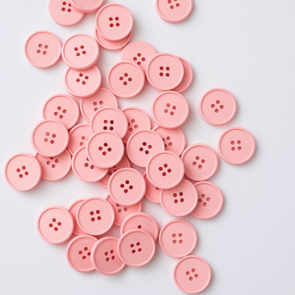 Pink buttons scattered on a light gray background