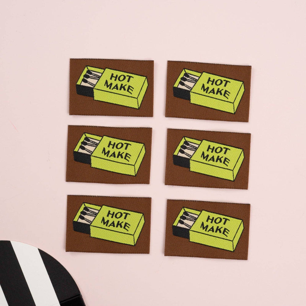 Five woven labels with matchbox with 'Hot Make' text on a pink background