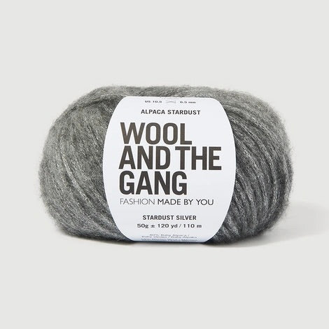A ball of Wool and the Gang's Alpaca Stardust yarn in Stardust Silver, featuring a white paper label with black text, set against a clean, light gray background.