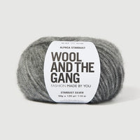 A ball of Wool and the Gang's Alpaca Stardust yarn in Stardust Silver, featuring a white paper label with black text, set against a clean, light gray background.