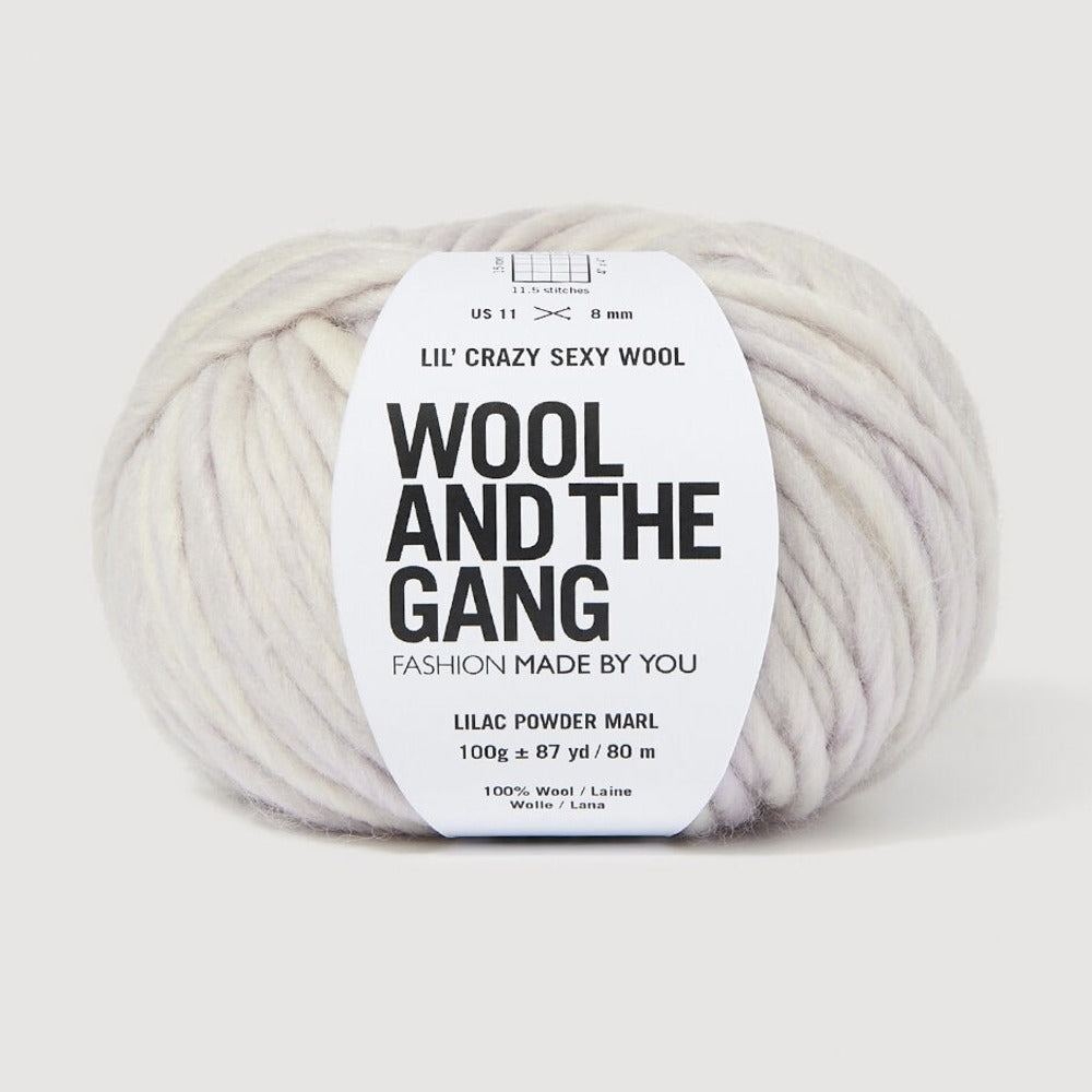 A skein of Lil' Crazy Sexy Wool by Wool and The Gang in Lilac Powder Marl, which is a variegated light purple and white colorway. 