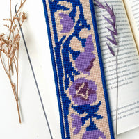Needlepoint bookmark with purple floral design on a white surface