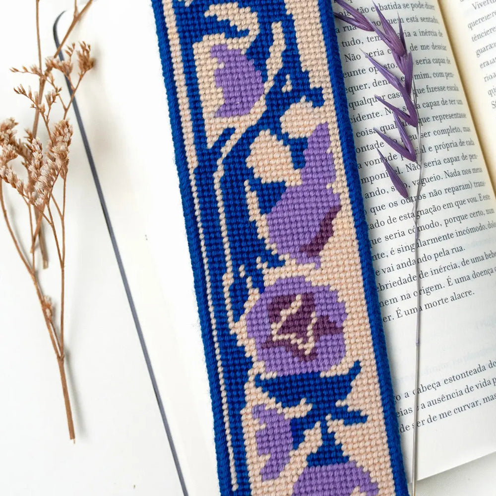 Needlepoint bookmark with purple floral design on a white surface