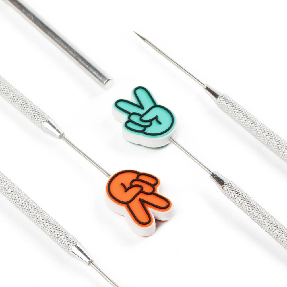 Two colorful peace sign needle protectors on a white background with silver tools.