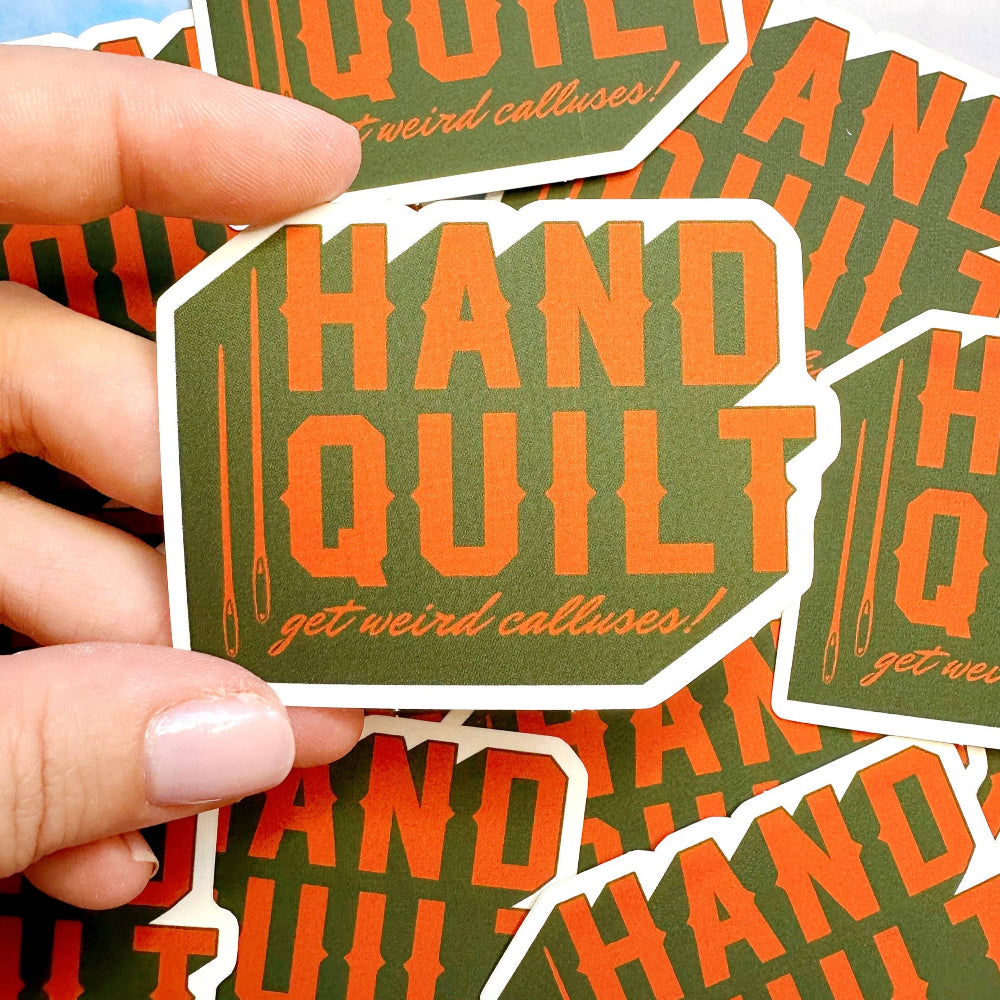 Hand quilt get weird calluses stickers with orange text on green background held by a hand.