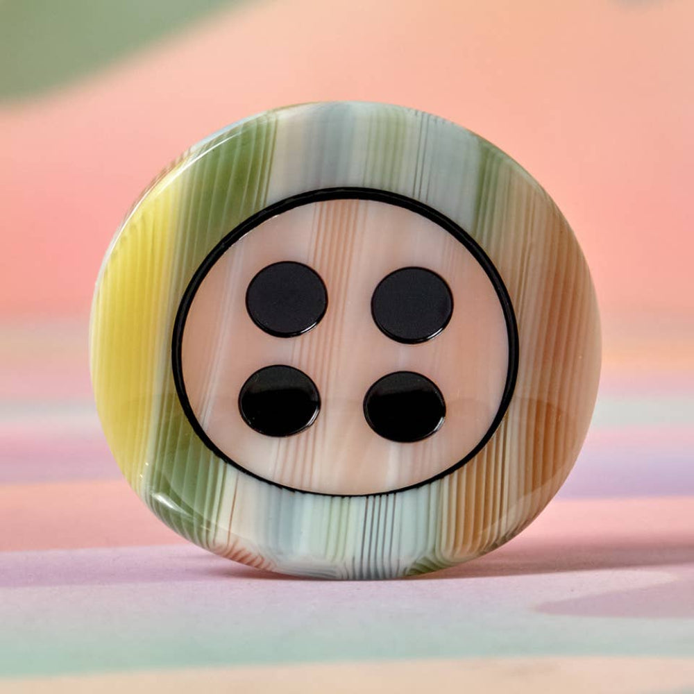 Multicolored button with black dots on a pastel background