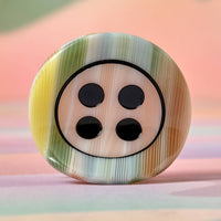 Multicolored button with black dots on a pastel background