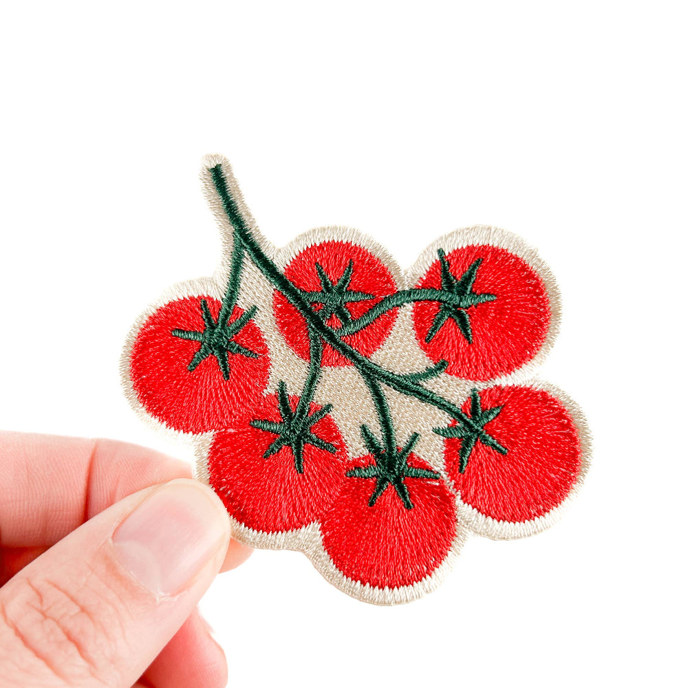 Embroidered patch of red tomatoes on a white background