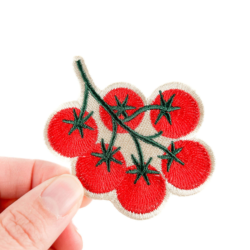 Embroidered patch of red tomatoes on a white background