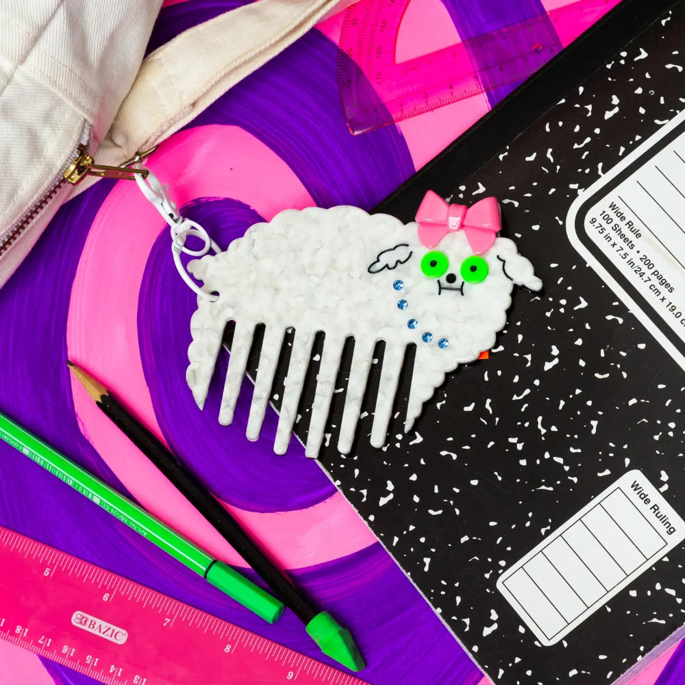 Decorative comb with dog character on a purple surface with stationery items