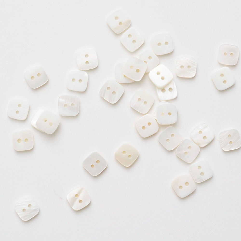 White buttons scattered on a white background