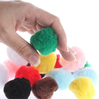 Colorful pom-poms held by a hand with a white background