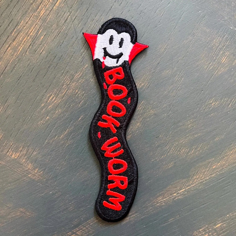 an embroidered bookmark featuring a bookworm dressed up as a vampire