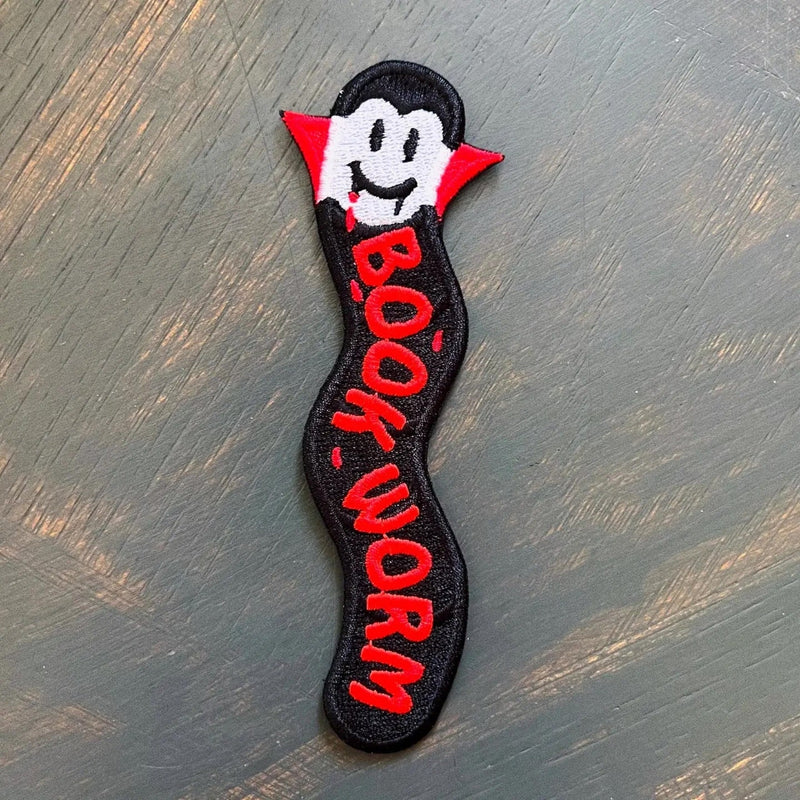 an embroidered bookmark featuring a bookworm dressed up as a vampire