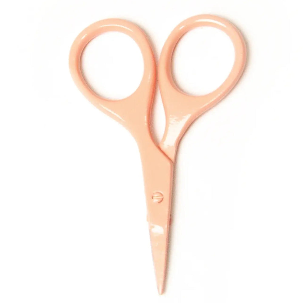 Pair of peach-colored scissors on a white background