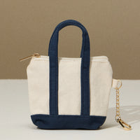 Mini tote bag with navy bottom and handles, zip top, and key chain on the side.
