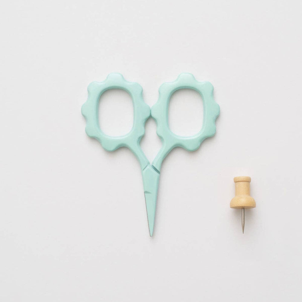 Light blue scissors and wooden pin on a light gray background