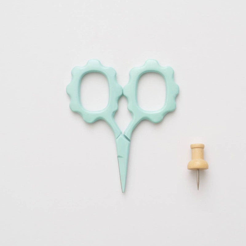 Light blue scissors and wooden pin on a light gray background