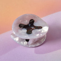 Clear plastic object with a black cross design on a pink background