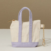 Mini tote bag with lavender bottom and handles, zip top, and key chain on the side.