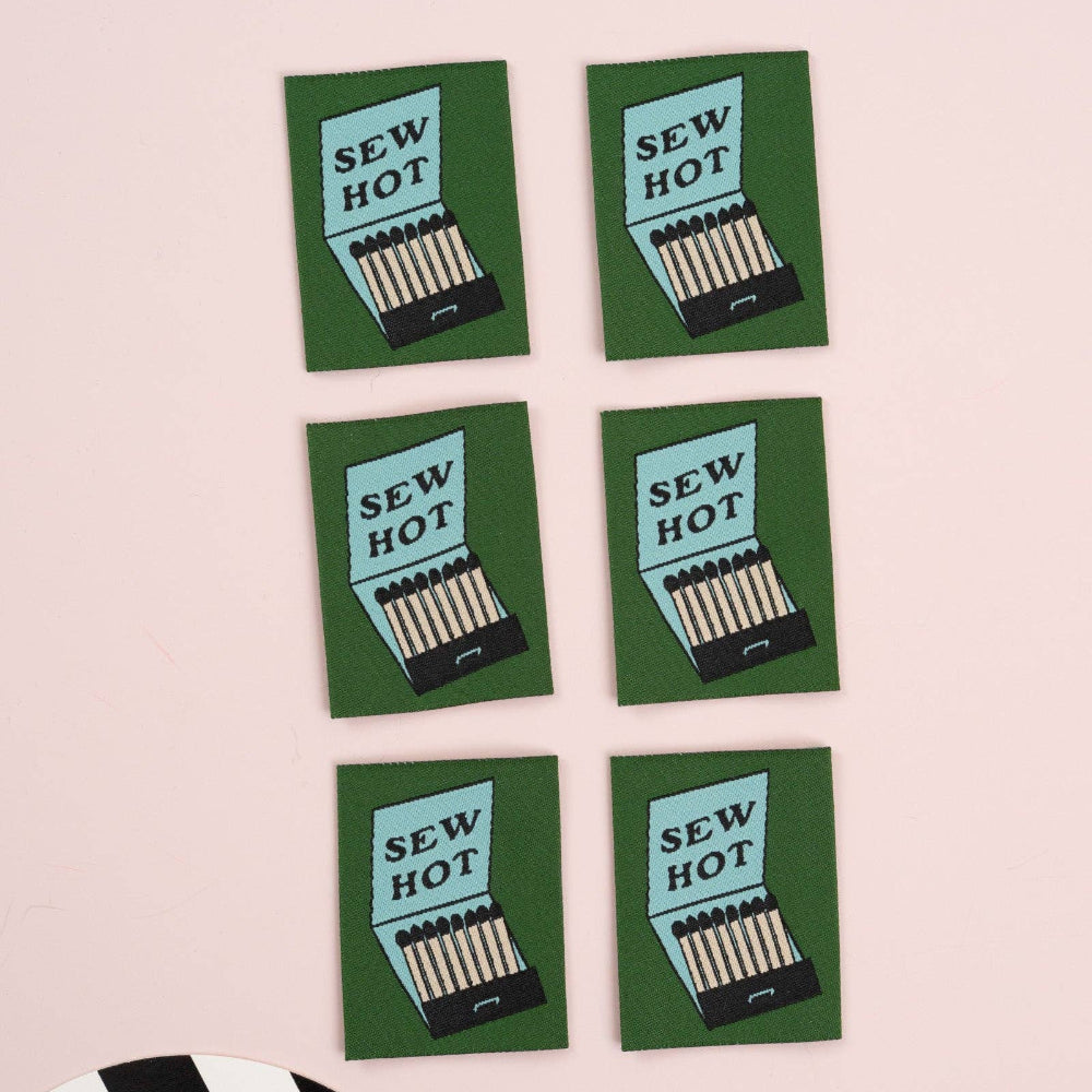 Six 'Sew Hot' matchbox labels on a pink background with a black and white striped object.