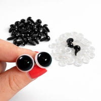 Black and white googly eyes with a hand holding two black eyes on a white background