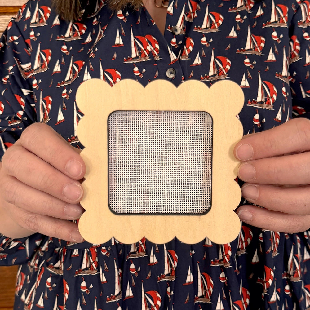 Person wearing a shirt with sailboat pattern holding a decorative frame.