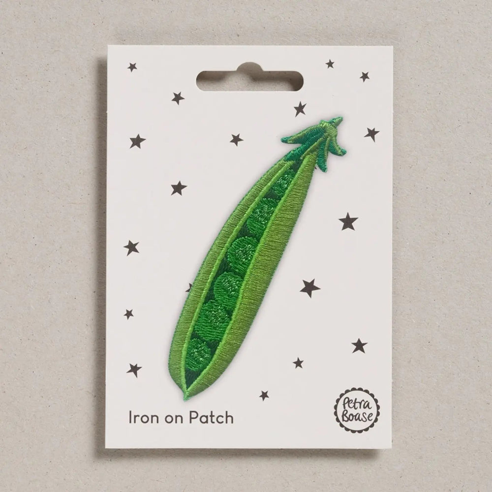 Green iron-on patch of a pea pod on a white card with star patterns, branded 'Petra Boase'.