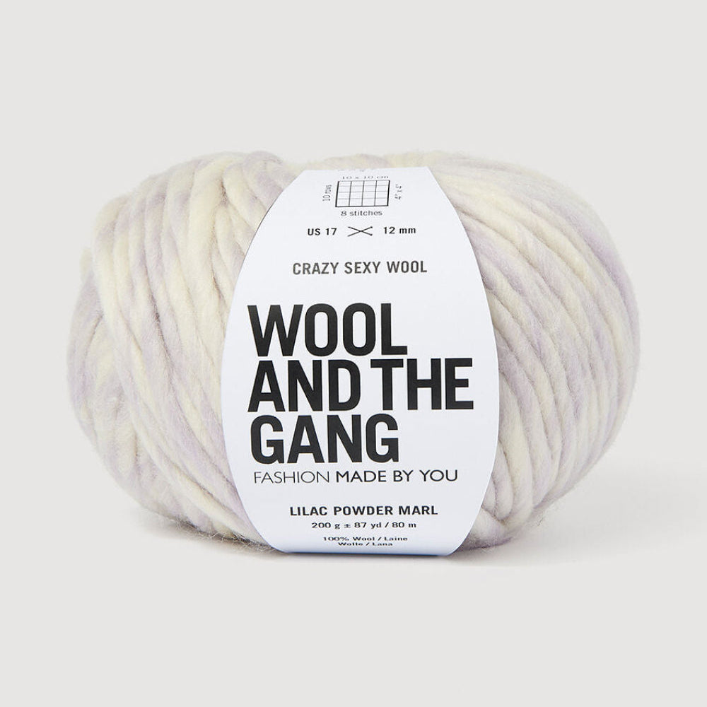 A ball of variegated yarn in lilac and cream shades, wrapped with a white paper label that reads 'WOOL AND THE GANG' and 'CRAZY SEXY WOOL'.
