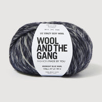 A skein of Lil' Crazy Sexy Wool by Wool and The Gang in Midnight Blue Marl, which is a variegated dark blue and white colorway. 