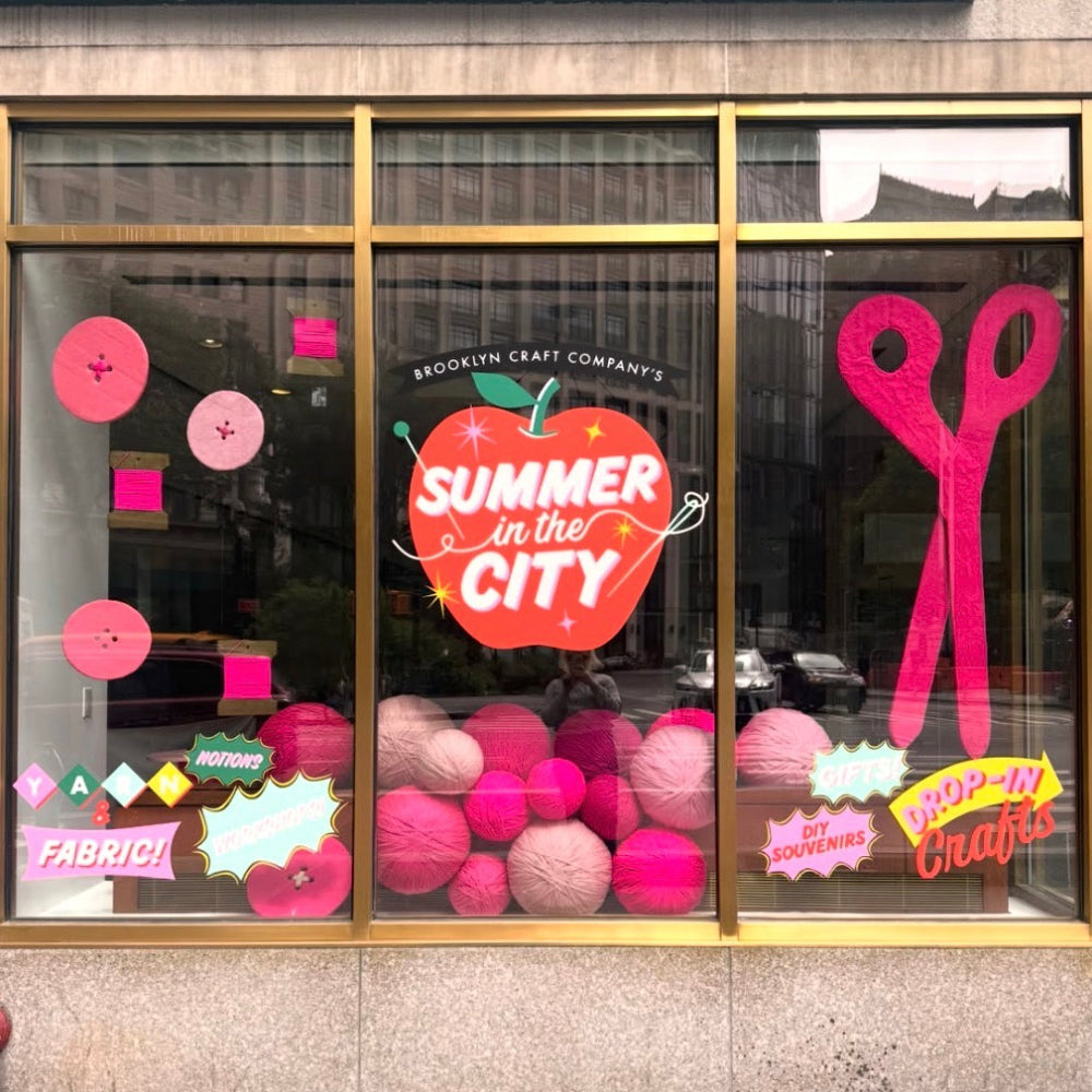Store window display with 'Summer in the City' theme featuring pink and red decorations.