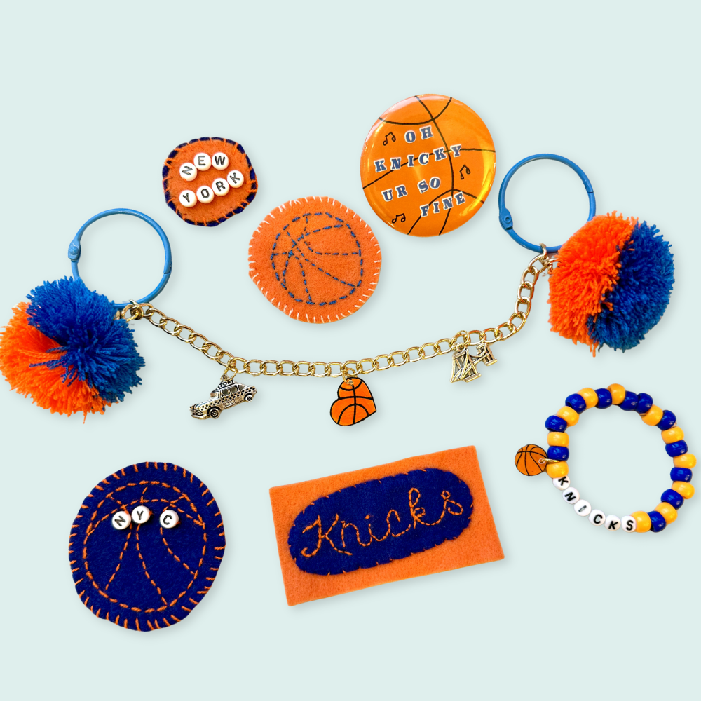 Collection of New York Knicks-themed keychains and charms on a light blue background