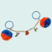 Keychain with pom-pom ends and various charms on a light blue background