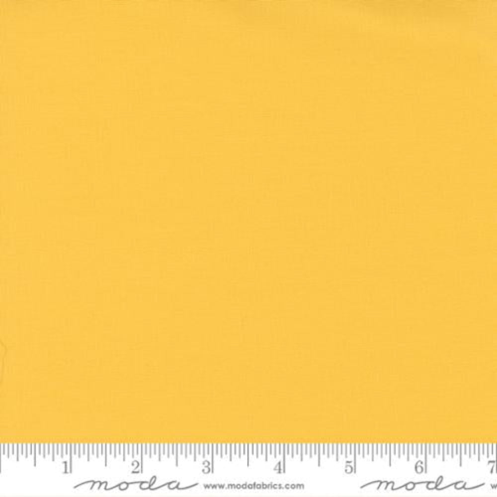Solid yellow fabric swatch with a ruler at the bottom for scale, featuring the Moda Fabrics logo.