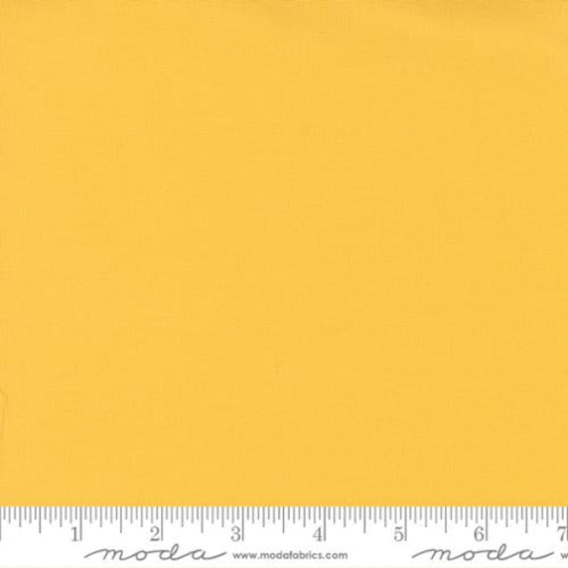 Solid yellow fabric swatch with a ruler at the bottom for scale, featuring the Moda Fabrics logo.
