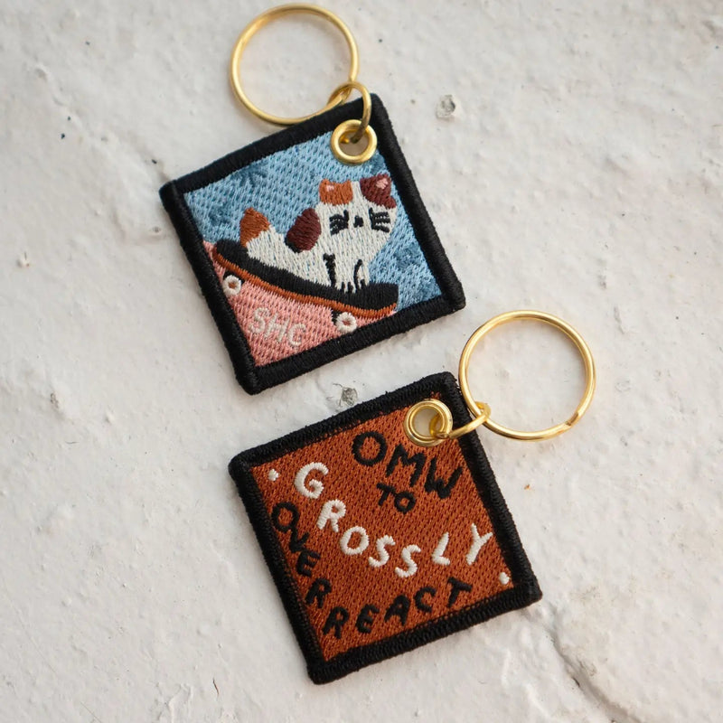 Two embroidered keychains on a textured white surface